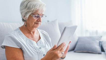 Senior woman with eyeglasses browsing on digital tablet