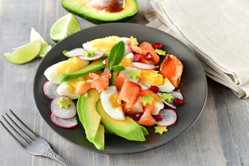Salad with organic avocado and with salmon, eggs and radish. Decorated with mint leaf and pomegranate. Healthy lunch, vegetarian food, diet dish. food for weight loss. Selective focus and copy space