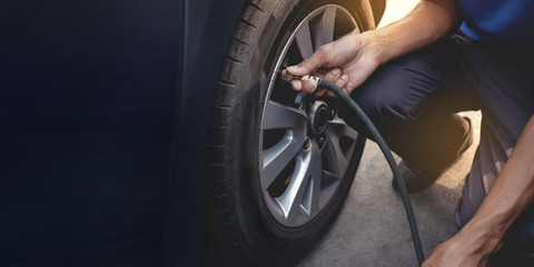 Man filling Air into the Tire. Car Driver Checking Air Pressure and Maintenance his Car by himself before Traveling - obrazy, fototapety, plakaty