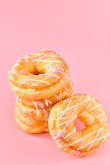 a lot of donuts, breakfast concept, the concept of calorie unhealthy diet, obesity, fat, pink background, selective focus