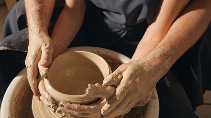 Fototapeta na wymiar Young couple making jug on potter's wheel, slow motion