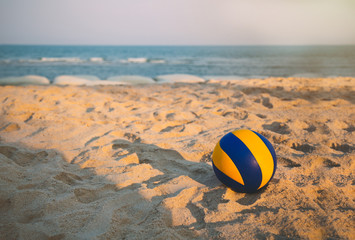 volleyball dropped on the beach in sunset with open sea and clear sky.