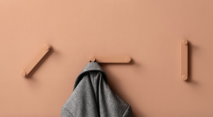 Fancy coral metal hangers with hanging gray jacket on colorful wall in studio
