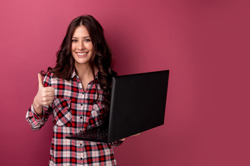 Portrait of an excited younggirl holding laptop computer and celebrating success isolated over gray background