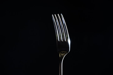 Fork on a black background with light from the side
