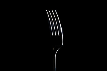 Fork on a black background with light from the side