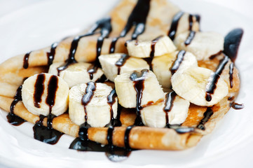 Thin delicious pancake with banana and chocolate on white background