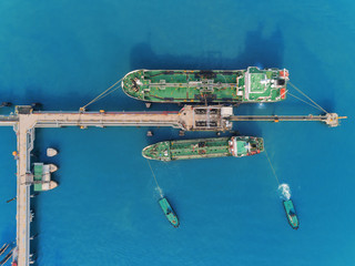 Aerial top view Tug boat drag Oil ship tanker from oil bridge for transportation from refinery on the sea.