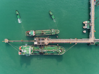 Aerial top view Tug boat drag Oil ship tanker from oil bridge for transportation from refinery on the sea.