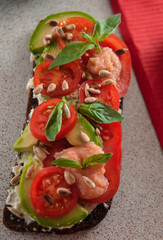 An avocado sandwich with tomatoes and cheeses. serving on the table
