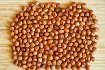 Hazelnut nuts lie on a light bamboo surface