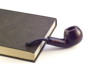 Smoking pipe next to a book on a white background.