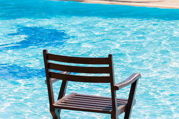 Deckchairs, chairs luxury swimming pool blue water for relaxation on summer travel vacation on the beach. Relaxing trip concept