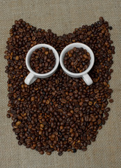 Owl made from coffee beans. Whole bean coffee. Coffee beans in the shape of an owl. Coffee cup on coffee beans. Coffee beans on burlap