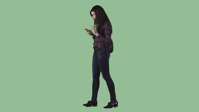 Pretty brunette girl is strolling and writing text message at iPhone. Alpha channel background