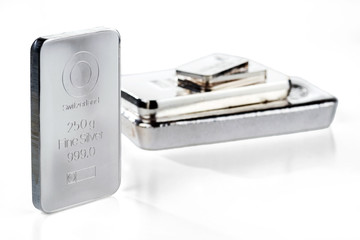 Minted silver ingot weighing 250 grams against a background of a stack of various silver ingots. Isolated on white background. Selective focus. .