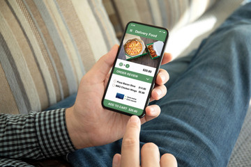 male hands holding phone with app delivery food on screen