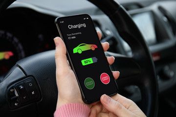 eco electric car women hand holding phone  with charging battery