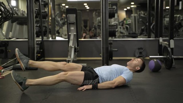 Image of a muscular man doing abdominal exercise at the gym.