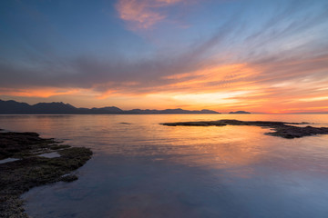 Rocks rock along the beach sand in the twilight. 