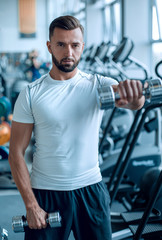 Fototapeta na wymiar close up.an attractive man works with dumbbells in the gym