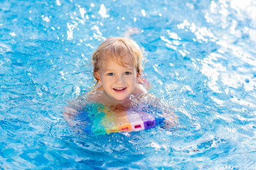 Child learning to swim. Kids in swimming pool.