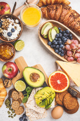 Healthy balanced breakfast on white background. Muesli, juice, croissants, cheese, biscuits and fruit, top view.