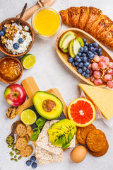 Healthy balanced breakfast on white background. Muesli, juice, croissants, cheese, biscuits and fruit, top view.