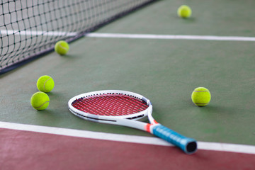 Tennis racket and ball on court after game.