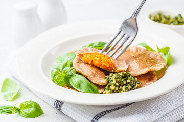 Pumpkin ravioli with pesto sauce in a white plate.