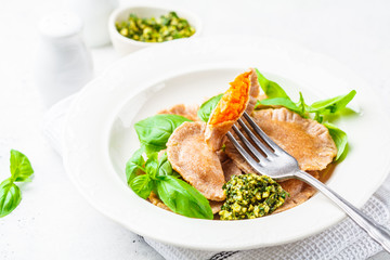 Pumpkin ravioli with pesto sauce in a white plate.