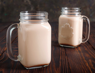 Two glass cups of hot cocoa with milk on  wooden table.
