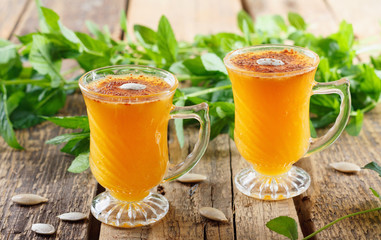 Healthy pumpkin fruit smoothie with seeds and mint leaves on table