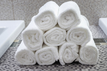 Fototapeta na wymiar Stack of clean white towels on ceramic countertop in bathroom
