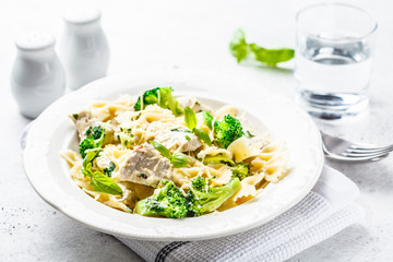 Italian pasta farfalle with broccoli, chicken and cheese in a white plate.