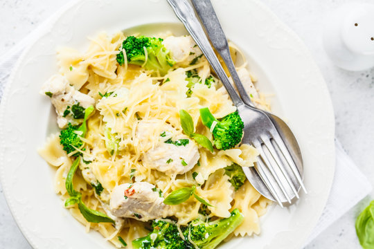 Italian pasta farfalle with broccoli, chicken and cheese in a white plate.