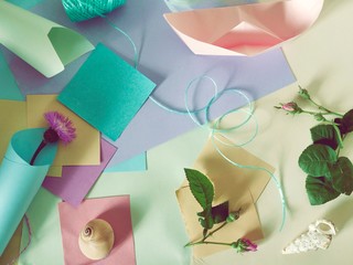 On a light background, top view, empty color paper for notes, spring decor, flower buds, delicate ribbon, paper boats, concept of congratulations, preparation for romantic holidays, women's day, mothe