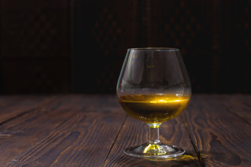 Glass of whiskey or brandy on wooden table