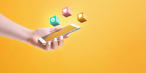Girl's hand holding smartphone in hand, surrounded with social media notification icons on yellow background