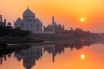 Fototapeta na wymiar Taj Mahal reflected in Yamuna river at sunset in Agra, India