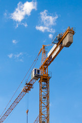 Yellow tower crane against a blue sky