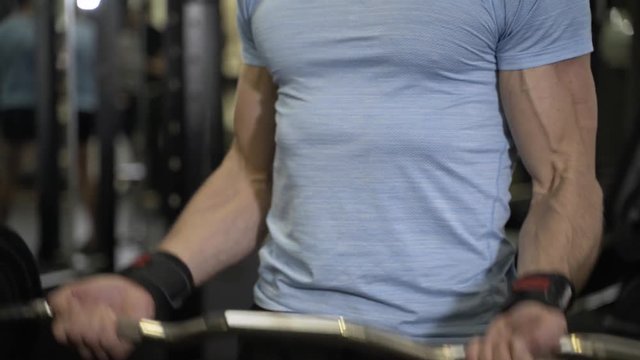 Close up image of man using barbell at the gym.
