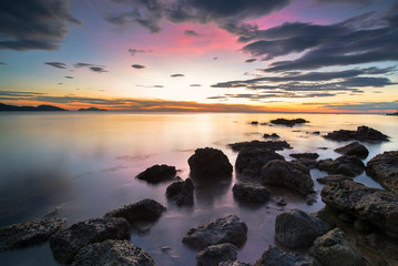 Fototapeta na wymiar Rocks rock along the beach sand in the twilight. 