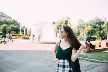 Brunette girl in a summer day in the city wearing round sunglasses