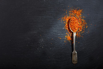 dried saffron spice in a spoon on dark table