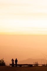 Fototapeta na wymiar Couple tourists enjoy sunrise view on the mountain peak.