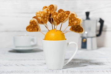 conceptual mini pancakes in the form of hearts for breakfast on white table