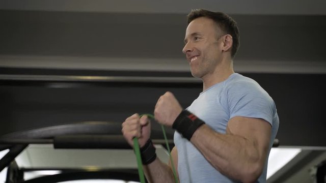 Close up image of man doing exercise with elastic band at the gym.