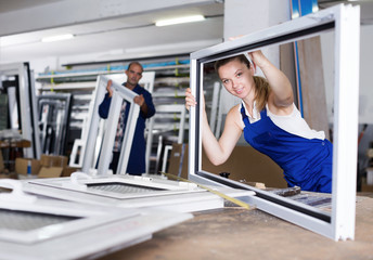 Young smiling female worker with plastic window frame