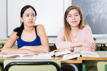 Fototapeta premium Young girl is thinking about successful her girlfriend at the desk